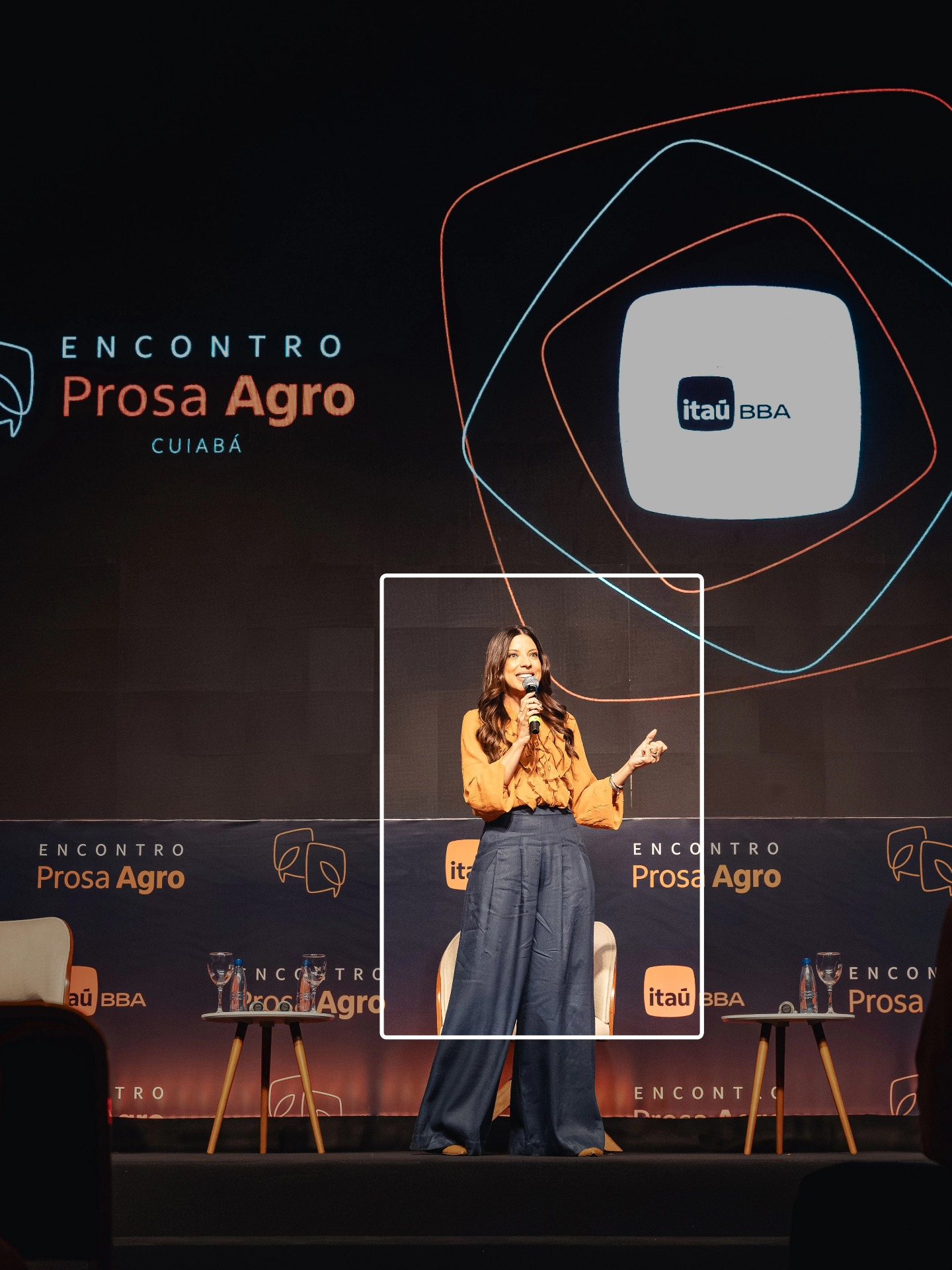 Palestrante sozinha no palco diante do telão com a marca do Encontro Prosa Agro